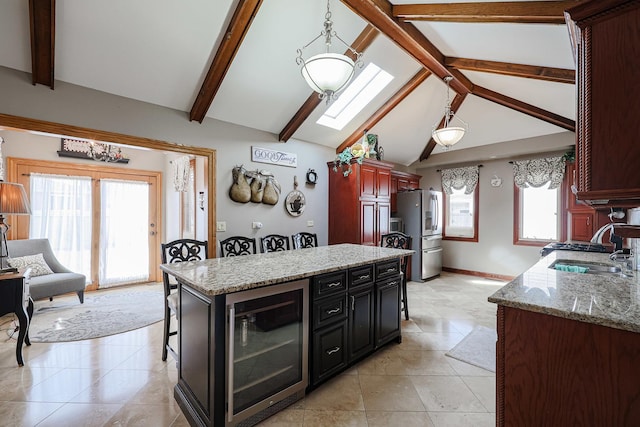 kitchen featuring stainless steel fridge with ice dispenser, beverage cooler, lofted ceiling with skylight, a kitchen breakfast bar, and a sink