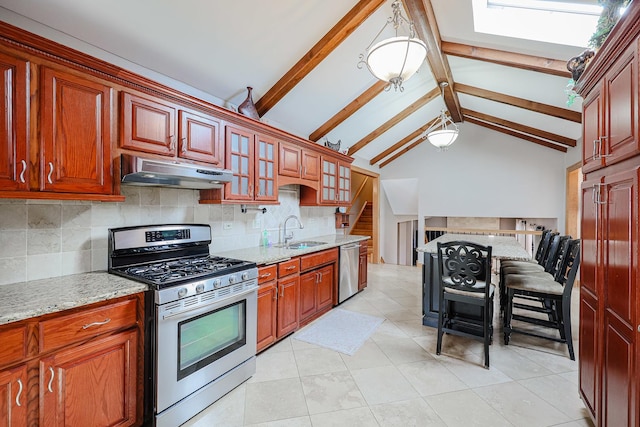 kitchen with light stone counters, a sink, decorative backsplash, appliances with stainless steel finishes, and under cabinet range hood