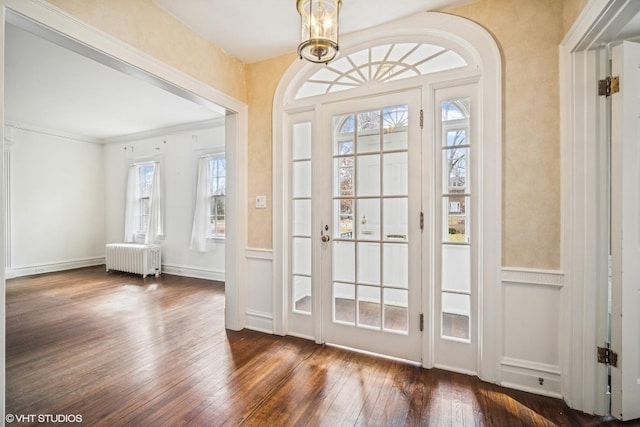 entryway with crown molding, arched walkways, dark wood finished floors, and radiator heating unit