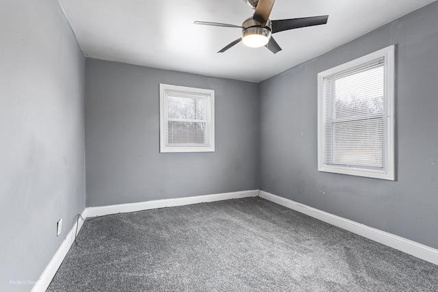 carpeted spare room featuring baseboards and a ceiling fan