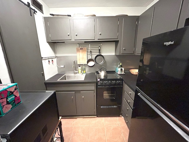 kitchen featuring black appliances, gray cabinets, dark countertops, and a sink