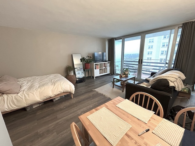 bedroom featuring access to exterior, floor to ceiling windows, and wood finished floors