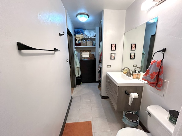 bathroom featuring a spacious closet, toilet, vanity, tile patterned flooring, and baseboards