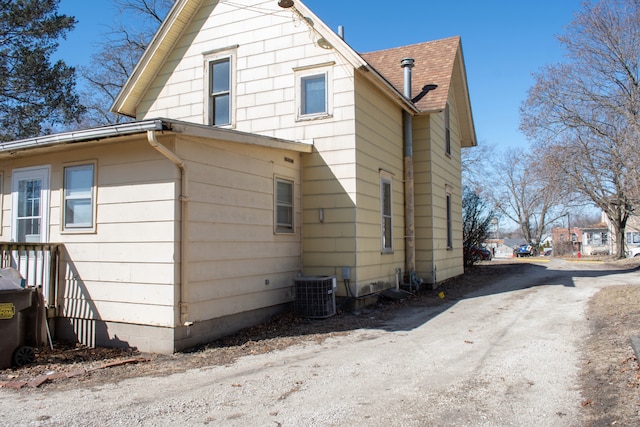 view of home's exterior with a shingled roof and cooling unit