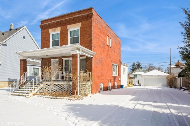 view of front of home featuring covered porch, brick siding, an outbuilding, and a detached garage