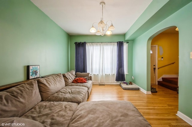 living area featuring stairway, baseboards, arched walkways, and wood finished floors