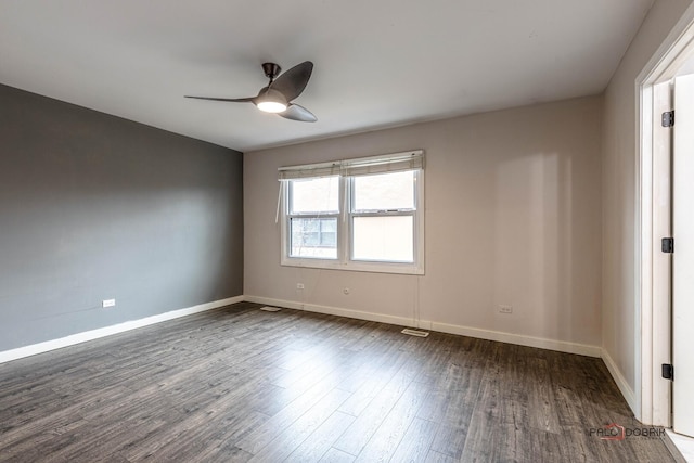 empty room featuring dark wood-style floors, ceiling fan, visible vents, and baseboards