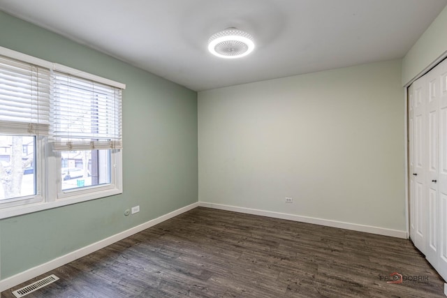 unfurnished bedroom featuring dark wood-type flooring, a closet, visible vents, and baseboards