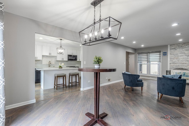 dining space with a stone fireplace, dark wood-type flooring, recessed lighting, and baseboards