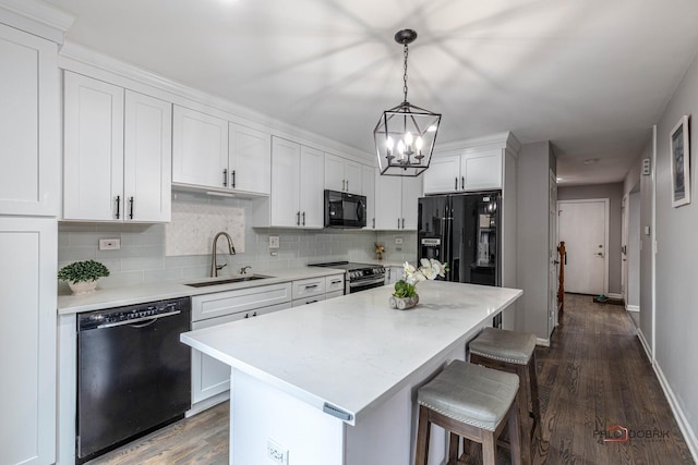 kitchen featuring black appliances, a kitchen bar, a sink, and light countertops