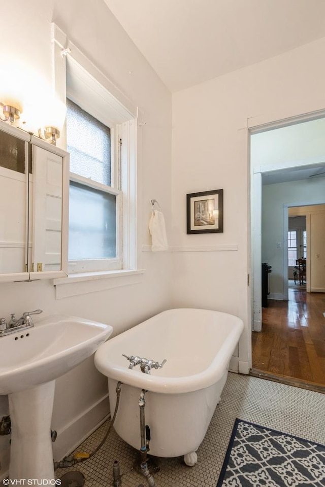 full bathroom featuring a sink, plenty of natural light, a freestanding bath, and tile patterned floors