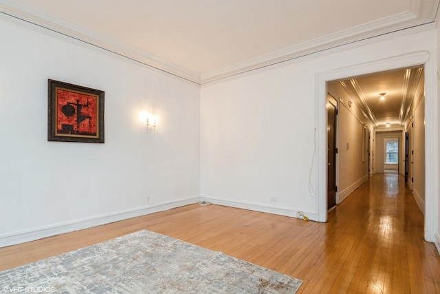 spare room with ornamental molding, light wood-style flooring, and baseboards