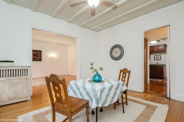 dining room featuring light wood-type flooring, beamed ceiling, baseboards, and ceiling fan