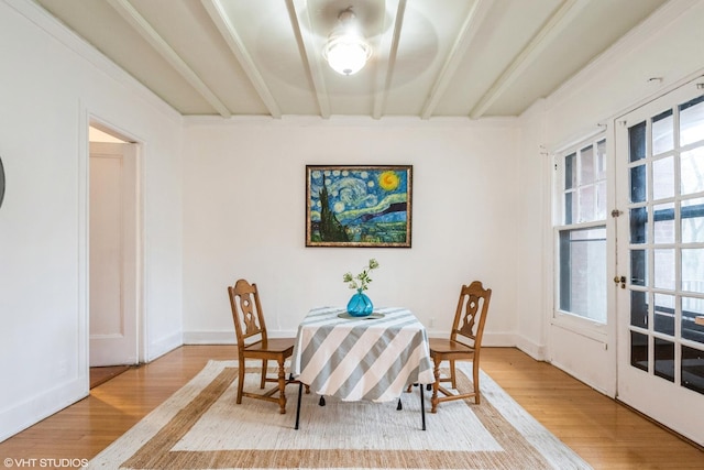 dining room with french doors, beamed ceiling, wood finished floors, and baseboards