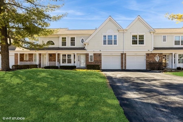 view of front of property featuring a porch, a garage, brick siding, driveway, and a front yard