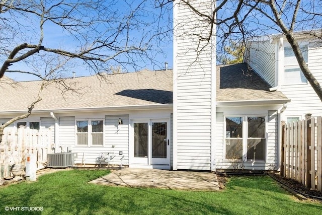 rear view of property featuring roof with shingles, a yard, a patio, central air condition unit, and fence