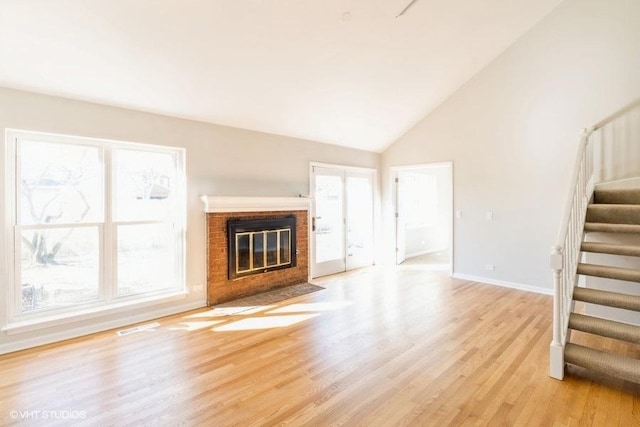 unfurnished living room with light wood-type flooring, plenty of natural light, stairs, and visible vents