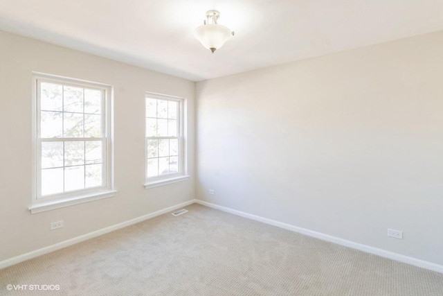 unfurnished room featuring baseboards, visible vents, and light colored carpet