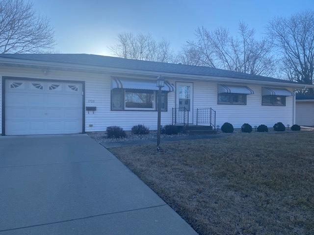 ranch-style house featuring a front yard, driveway, and an attached garage