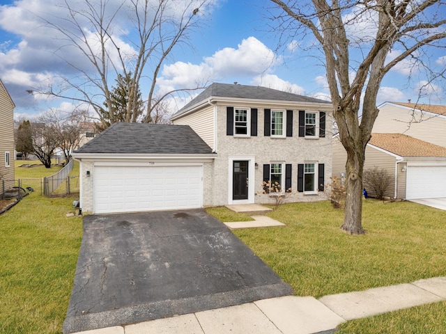 colonial-style house with a garage, fence, a front lawn, and aphalt driveway