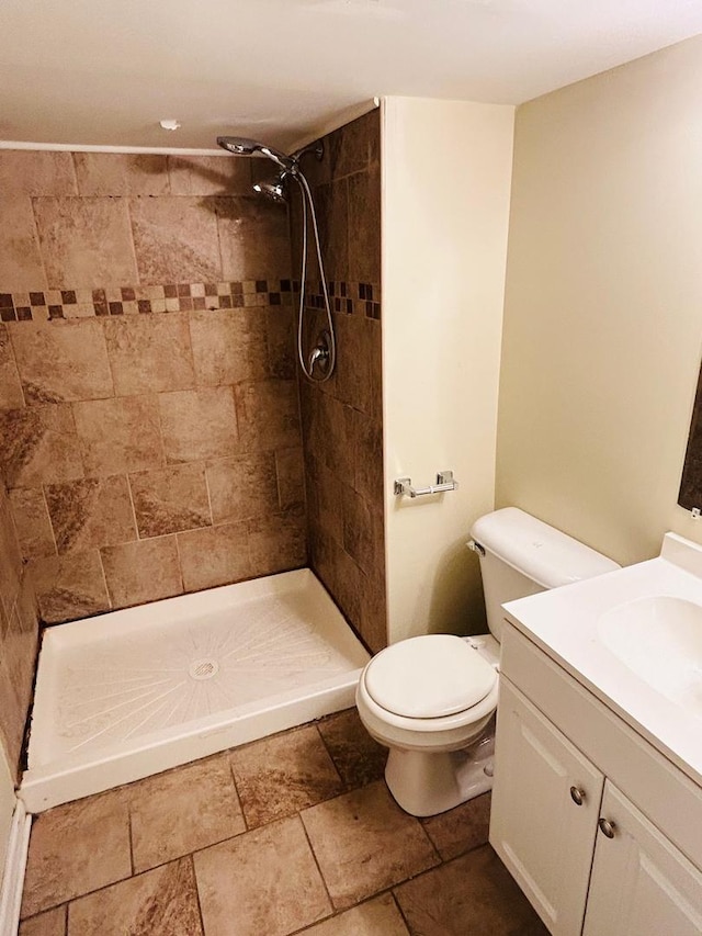 full bathroom featuring vanity, stone tile flooring, a shower stall, and toilet