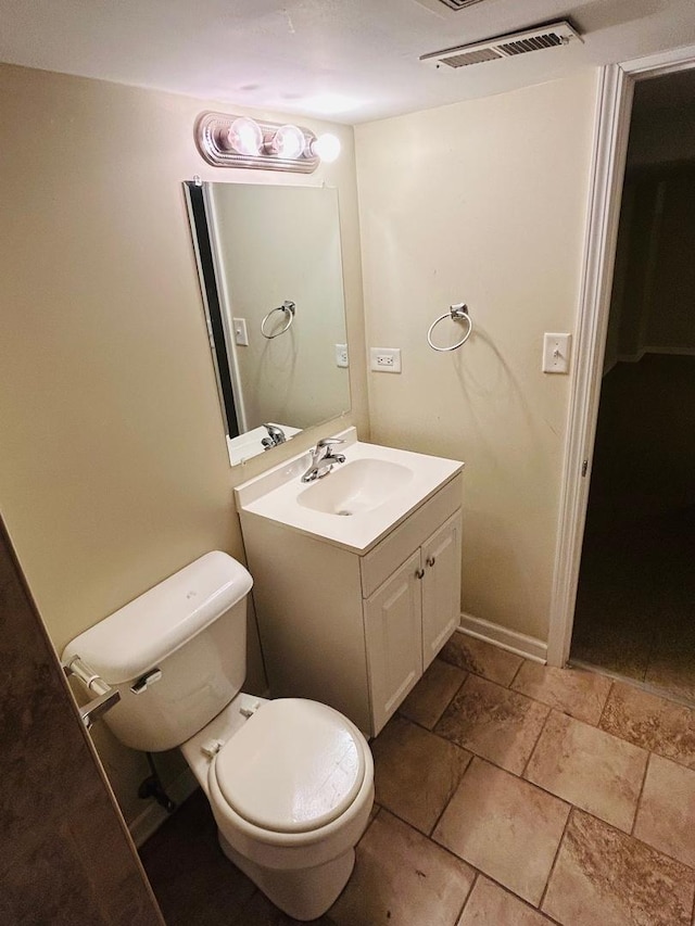 bathroom with stone tile flooring, visible vents, toilet, vanity, and baseboards