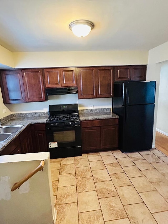 kitchen with light tile patterned floors, under cabinet range hood, a sink, dark brown cabinets, and black appliances