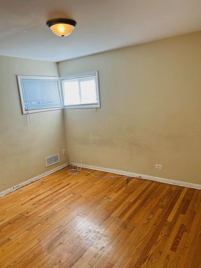 unfurnished room featuring baseboards, visible vents, and light wood-style floors