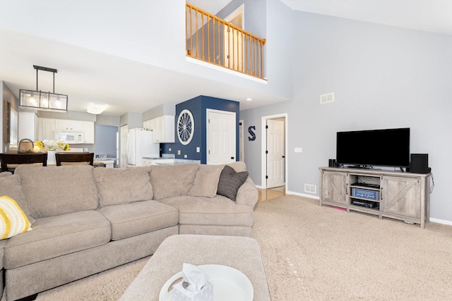 living room featuring a high ceiling, light colored carpet, visible vents, and baseboards