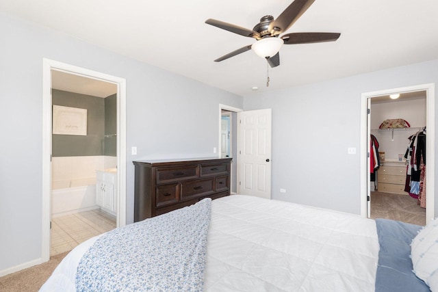 bedroom featuring ceiling fan, a spacious closet, a closet, ensuite bathroom, and light carpet