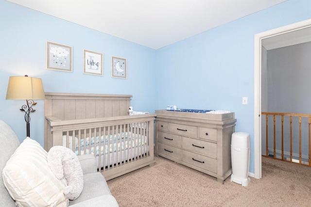 bedroom featuring baseboards, a nursery area, and carpet flooring