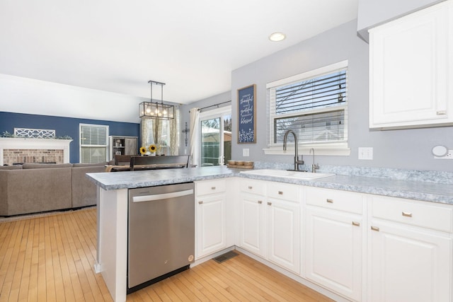 kitchen featuring stainless steel dishwasher, light countertops, light wood finished floors, and a sink