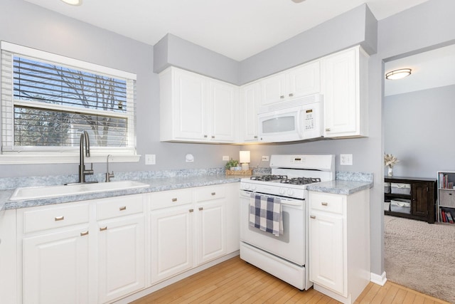 kitchen featuring a sink, white appliances, light wood-style floors, white cabinets, and light countertops