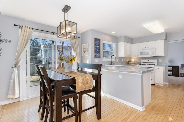 dining space with light wood-style flooring, a healthy amount of sunlight, and baseboards