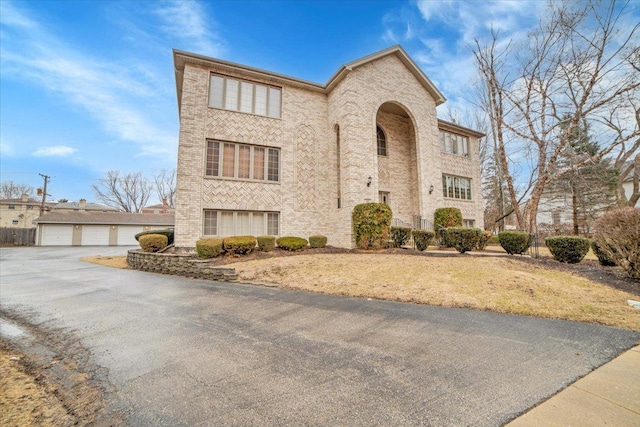 view of front of home with community garages, an outdoor structure, and brick siding