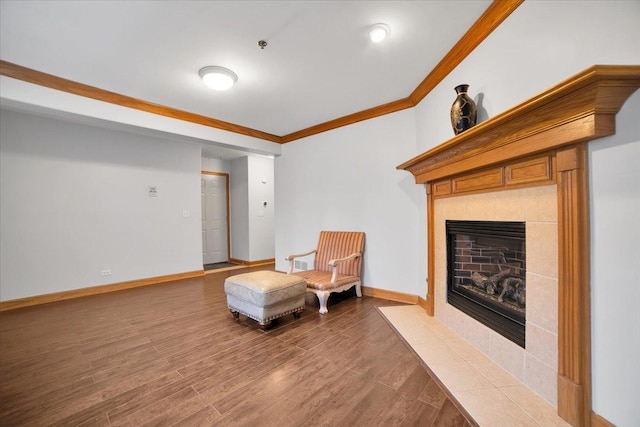 living area with a tile fireplace, crown molding, baseboards, and wood finished floors