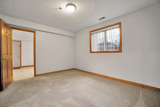 empty room with visible vents, light carpet, baseboards, and light tile patterned floors