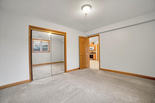 unfurnished bedroom featuring baseboards, a closet, and light colored carpet