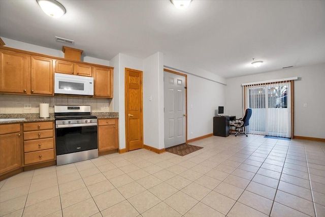 kitchen featuring light tile patterned floors, white microwave, backsplash, brown cabinets, and stainless steel electric range oven