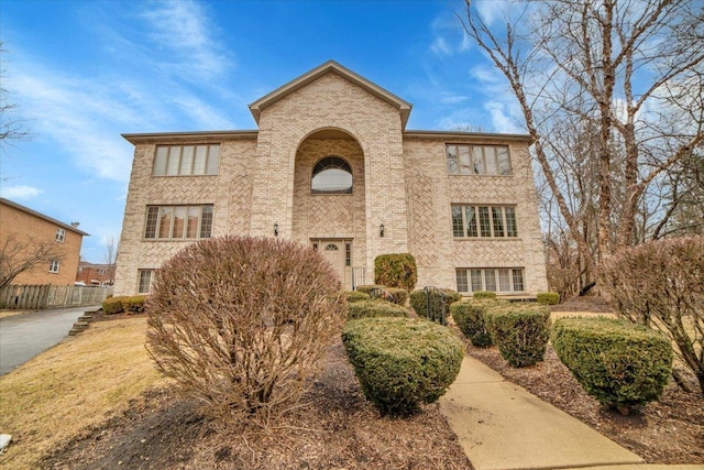 view of front of home with brick siding and fence