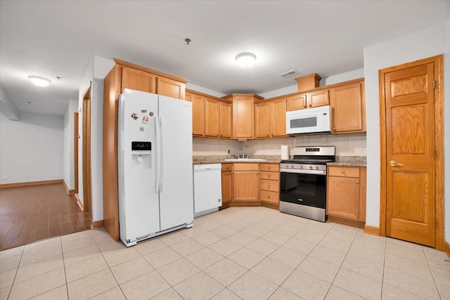 kitchen featuring visible vents, backsplash, light tile patterned flooring, a sink, and white appliances