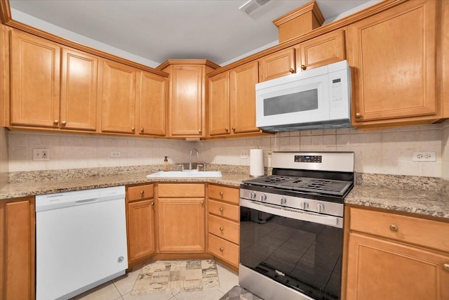 kitchen with light stone counters, visible vents, backsplash, a sink, and white appliances