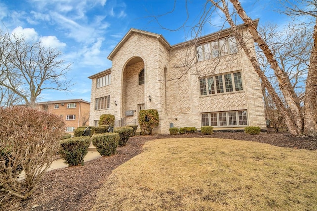 view of front of home featuring brick siding and a front lawn