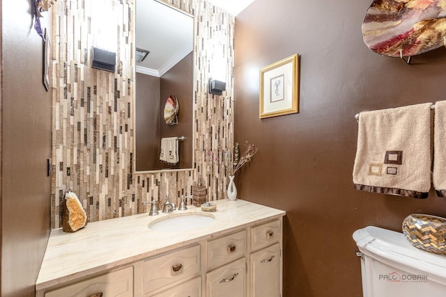 bathroom featuring toilet, ornamental molding, and vanity