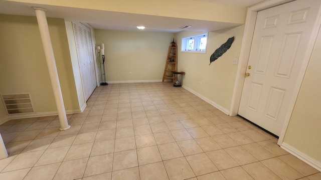 below grade area with light tile patterned flooring, visible vents, and baseboards