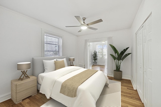 bedroom with a closet, radiator, baseboards, and wood finished floors