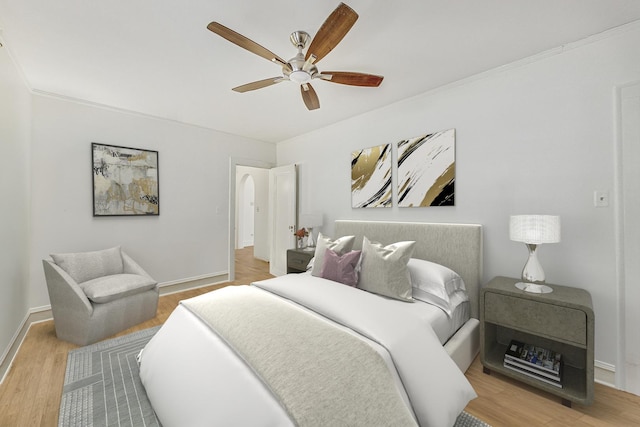 bedroom featuring arched walkways, wood finished floors, a ceiling fan, and baseboards