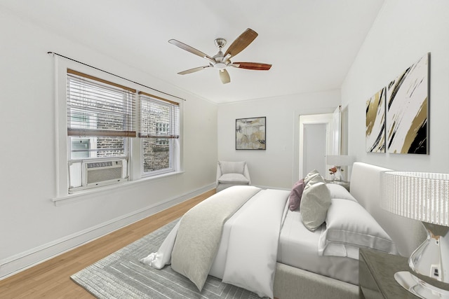 bedroom featuring a ceiling fan, baseboards, cooling unit, and wood finished floors