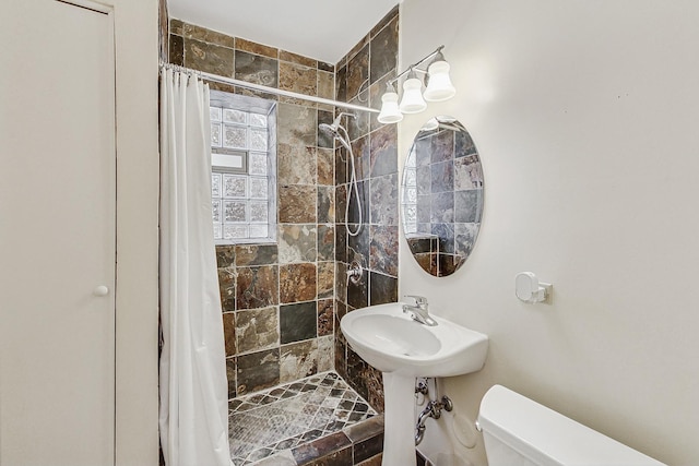 full bathroom with a sink, a tile shower, and toilet