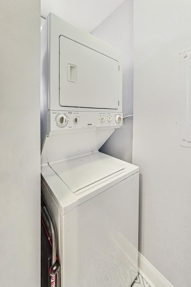 washroom featuring laundry area, baseboards, and stacked washer / dryer